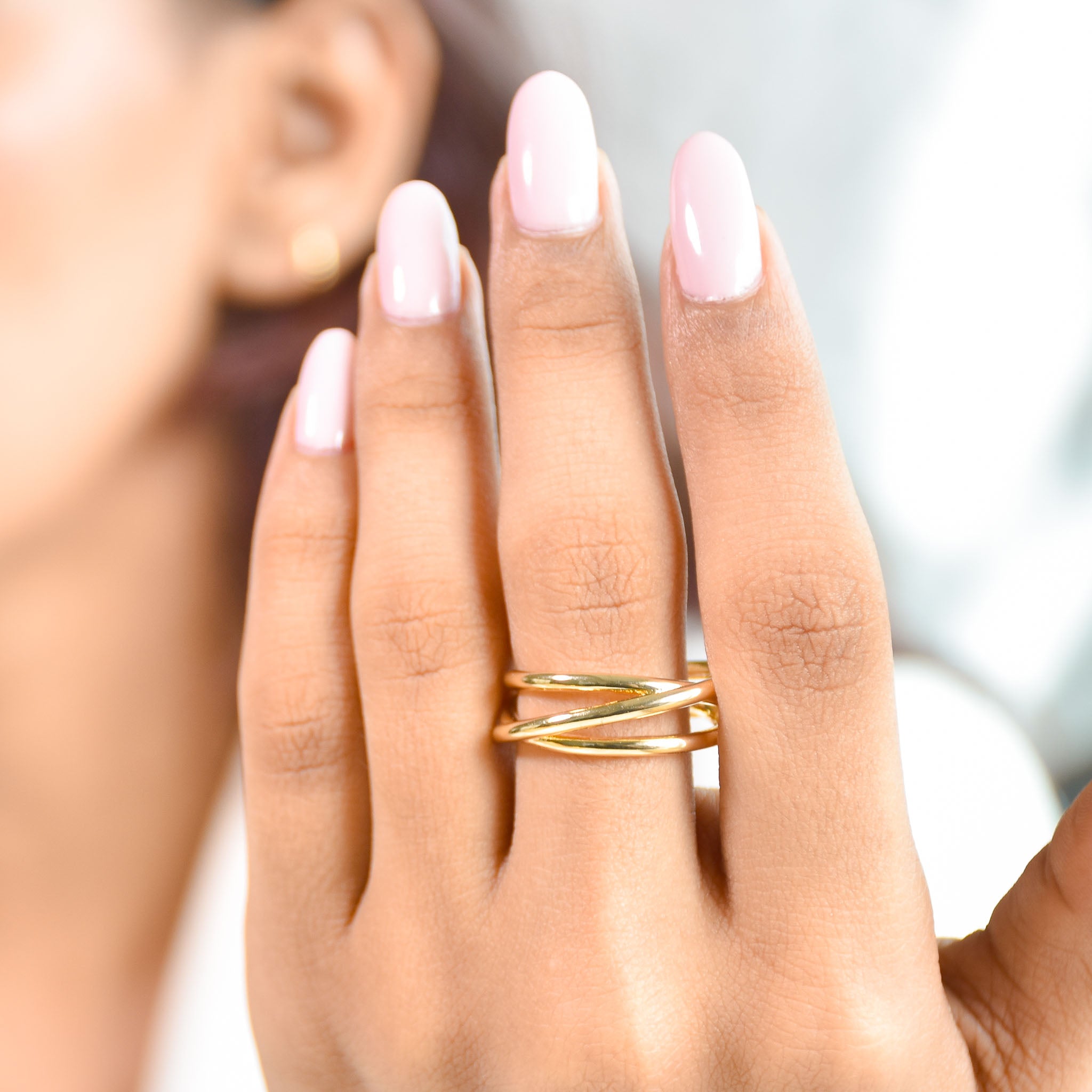 A three-piece gold ring stack featuring a criss-cross entwine band, a structured interlink design, and a bold fluid spiral statement ring.