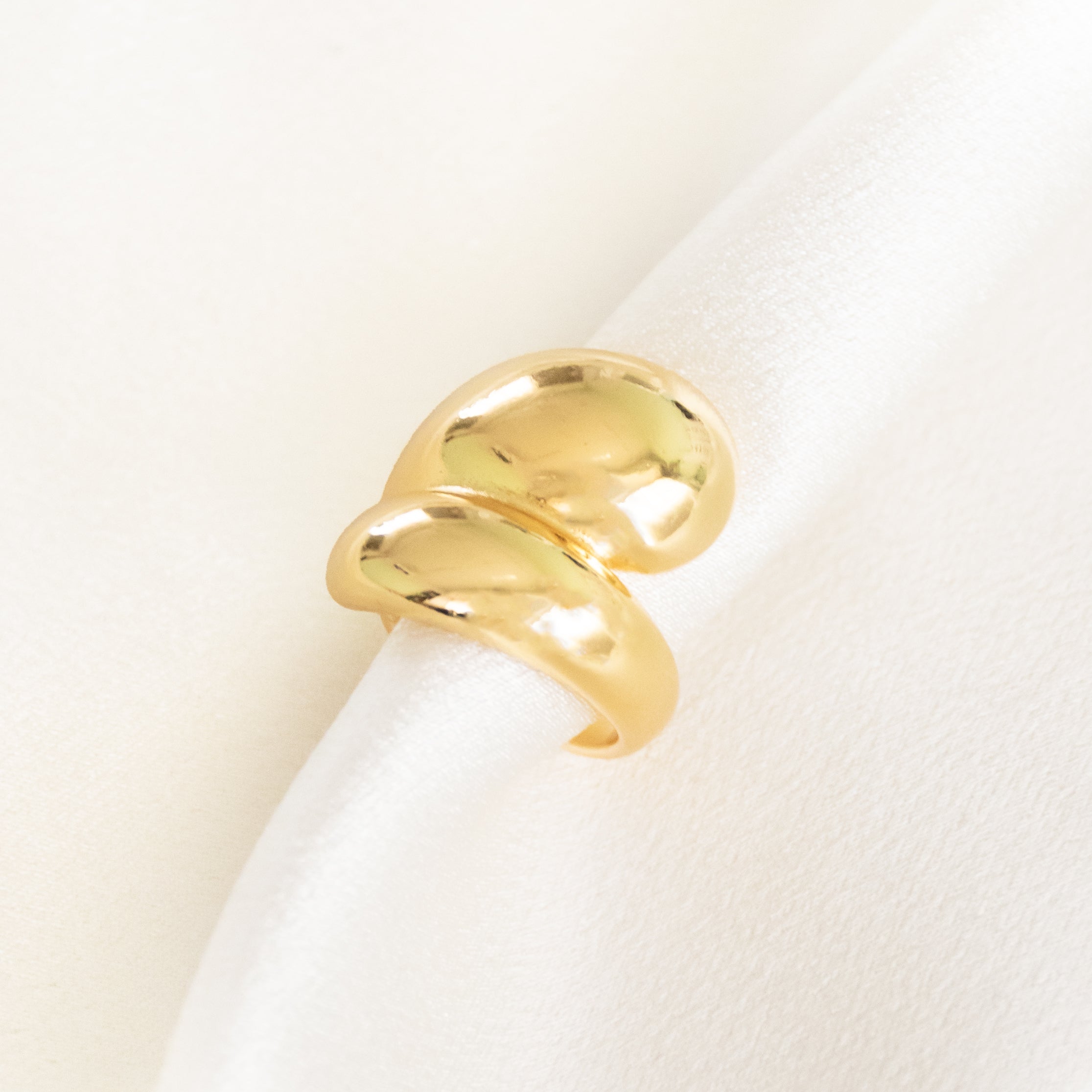 A three-piece gold ring stack featuring a criss-cross entwine band, a structured interlink design, and a bold fluid spiral statement ring.