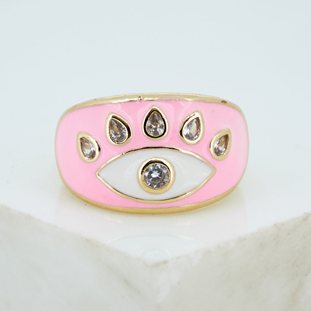 A stack of three adjustable gold rings featuring a pastel evil eye, a celestial moon motif, and a personalized initial charm.