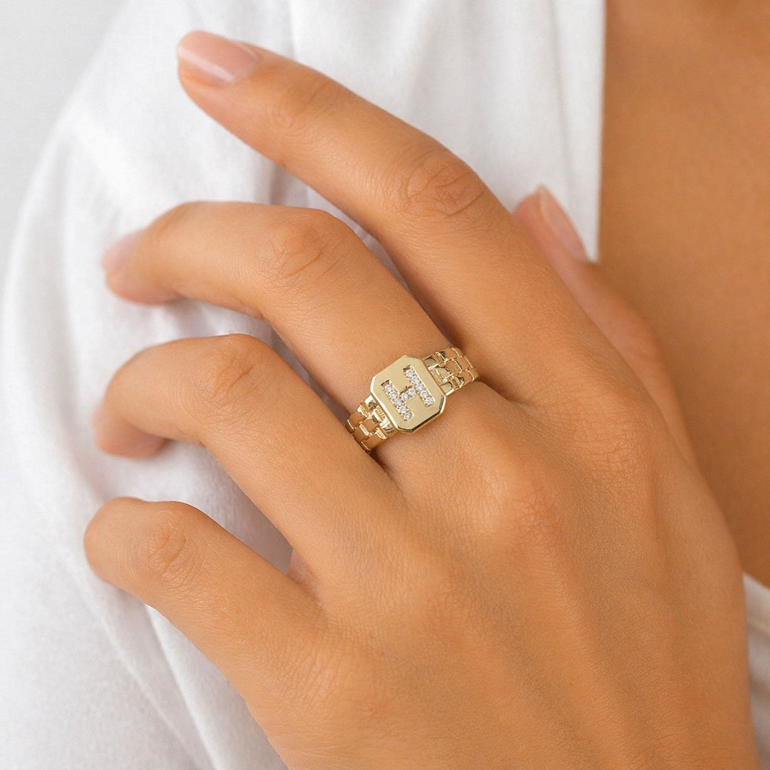 A stack of three adjustable gold rings featuring a pastel evil eye, a celestial moon motif, and a personalized initial charm.