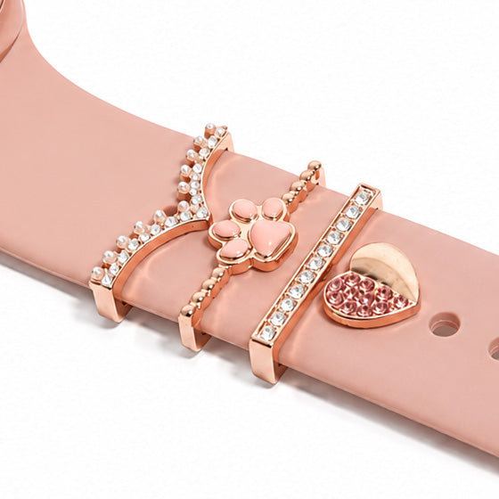 Rose gold smartwatch band styled with decorative heart, flower, pearl and crystal charms on a clean white background.