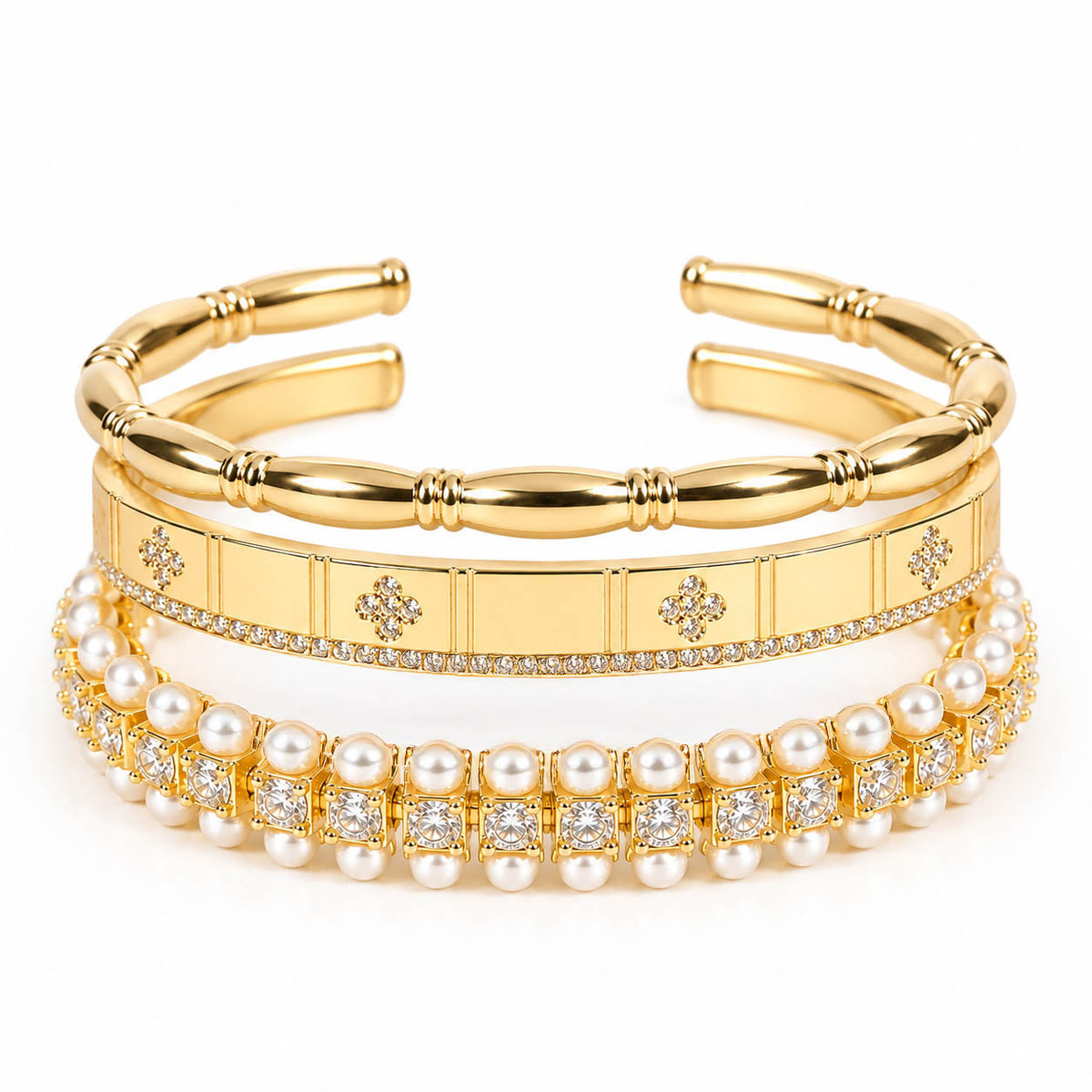 A product photo of a stacked set of gold-tone bracelets featuring segmented bamboo-style cuffs, a panel band with rhinestone clovers, and a double-row pearl and crystal bracelet.