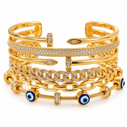 A studio shot of a curated stack of luxury gold bracelets, showcasing multiple designs including a paved diamond band, interlocking curb links, nail-inspired wrap cuffs, and a cable wire bracelet accented with blue and white evil eye beads.   