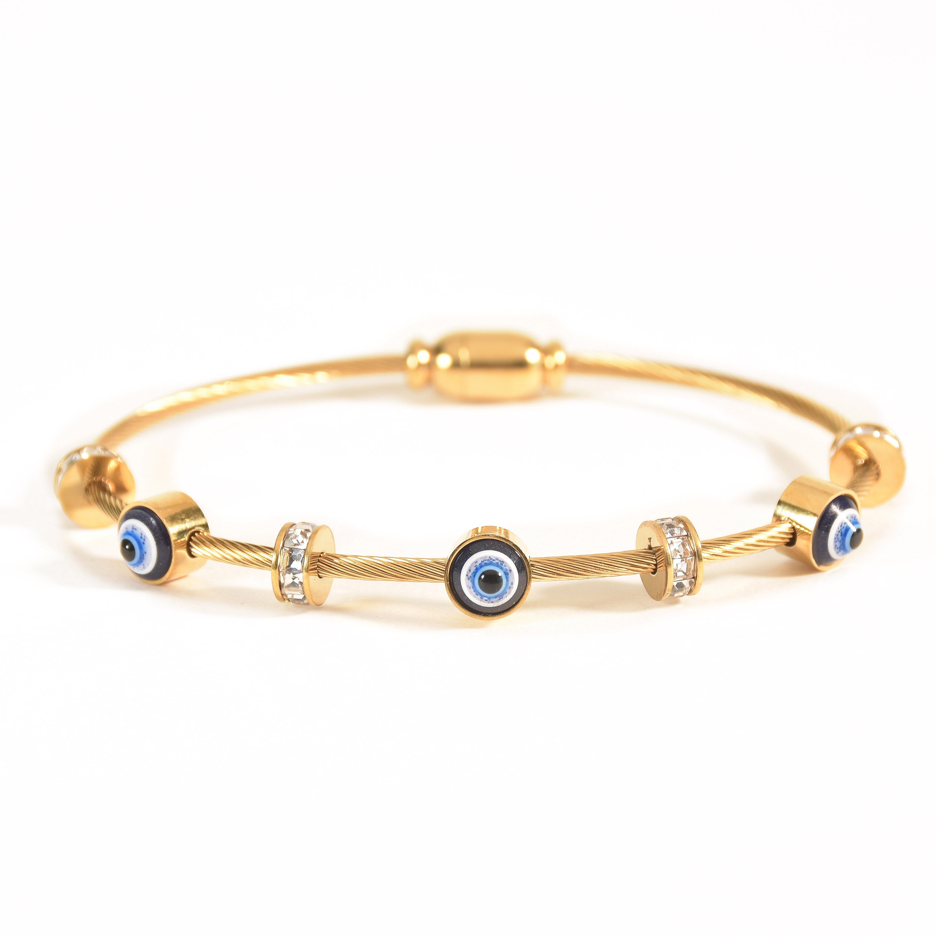 Gold bangle stack featuring a nail studded thick bangle, twisted studded link design, and evil eye accent, combining bold structure, fluid sparkle, and versatile statement styling.