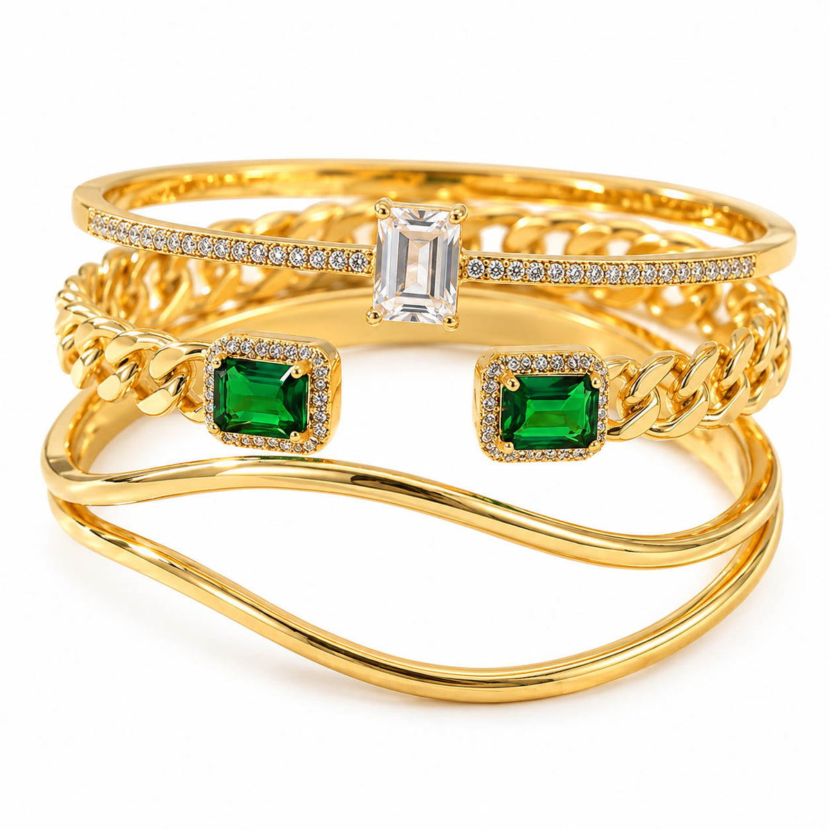 A product photo of a stacked set of gold bangles featuring an emerald-cut clear crystal center, vibrant green emerald-cut side stones with pave frames, and smooth wavy bands.