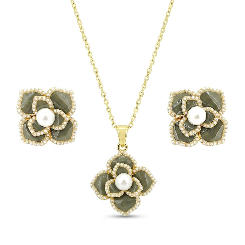 Gold floral necklace set with green stone petals and pearl center.
Includes matching stud earrings on a clean white background.