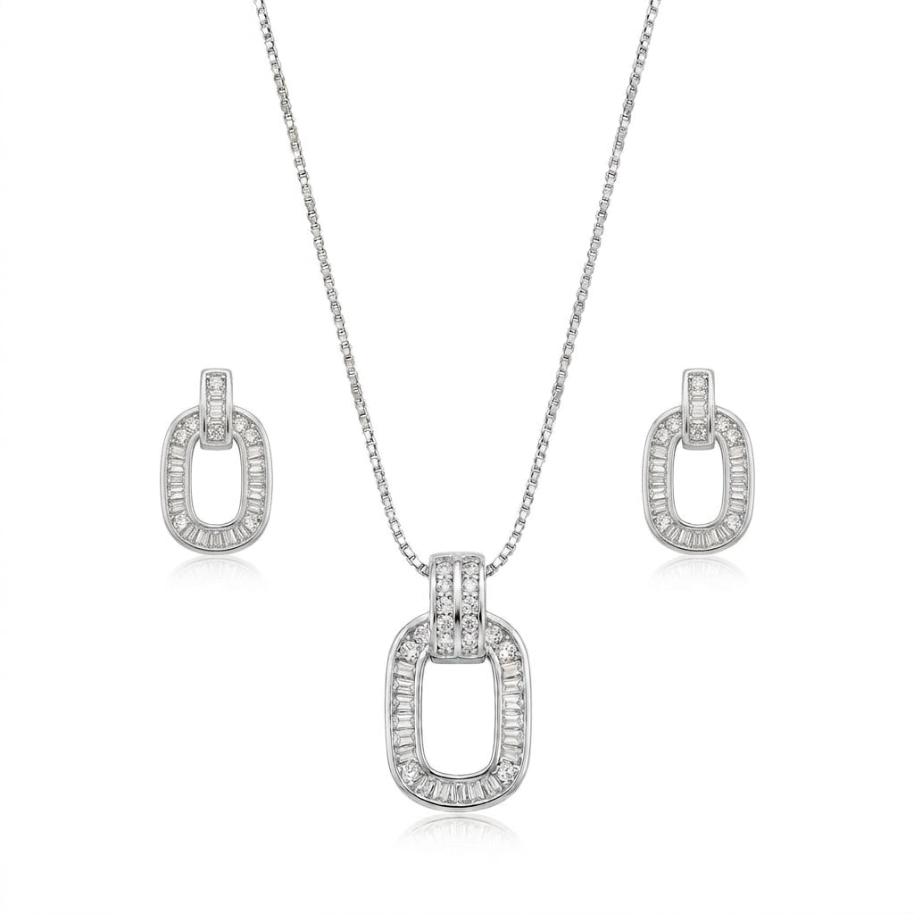 A silver jewelry set isolated on a plain white background, featuring a box-chain pendant necklace and matching drop earrings. The design showcases an open oval motif bordered with channel-set baguette cubic zirconia stones, suspended from a double-row pavé-set bail for a sophisticated, modern look.