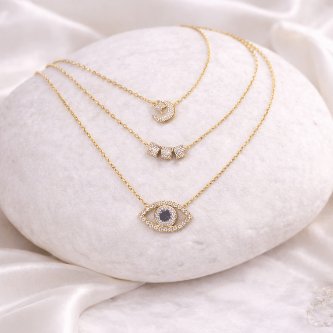Sparkle Suite Necklace Stack with Crescent Moon & Star, Triple Barrel, and Oceanic Evil Eye layered gold necklaces with crystal detailing