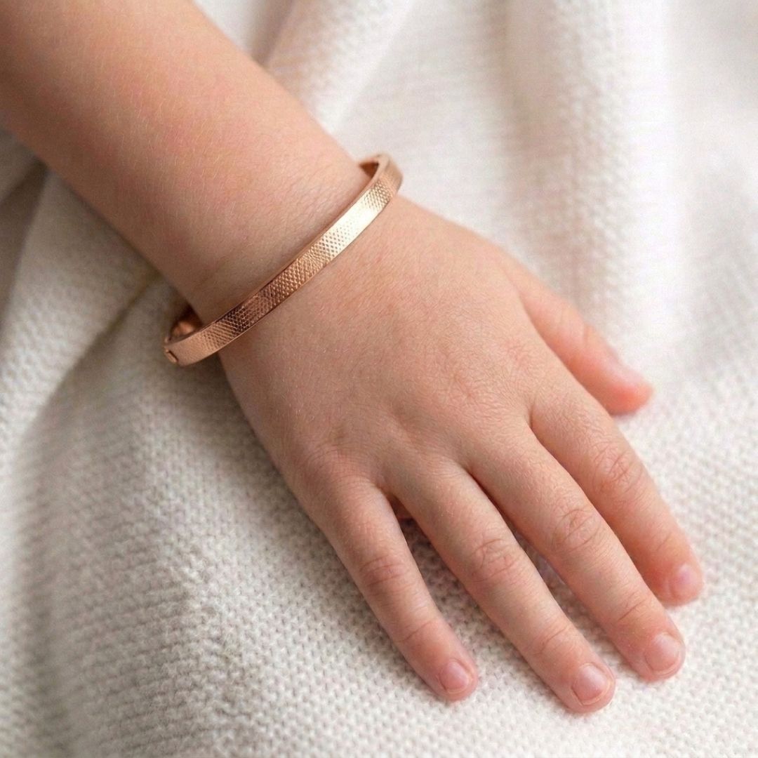 Minimalist gold stainless steel bangle bracelet with a slim textured band and secure hinged clasp, displayed on a clean white background.