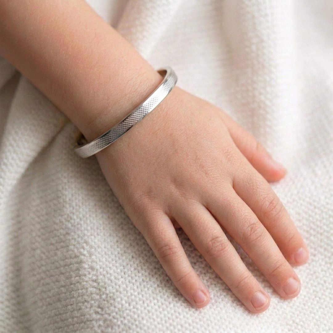 Minimalist gold stainless steel bangle bracelet with a slim textured band and secure hinged clasp, displayed on a clean white background.