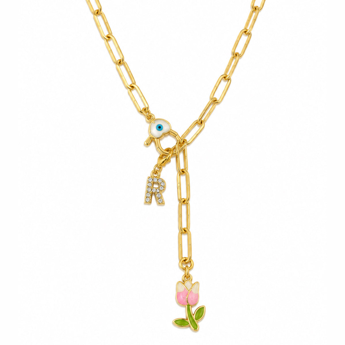 Gold-plated paperclip chain necklace with a blue Evil Eye centerpiece, sparkling “R” initial charm, and dangling pink tulip charm with green leaves, displayed on a clean white background.