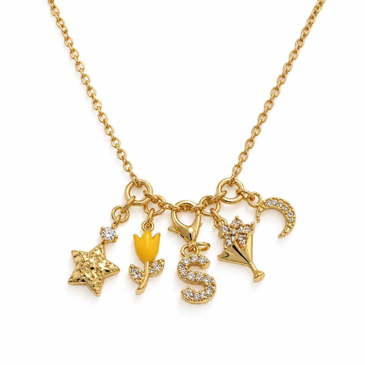 Gold-plated charm necklace featuring a star, yellow tulip, sparkling “S” initial, floral champagne glass, and crescent moon charms on a delicate chain, displayed on a clean white background.