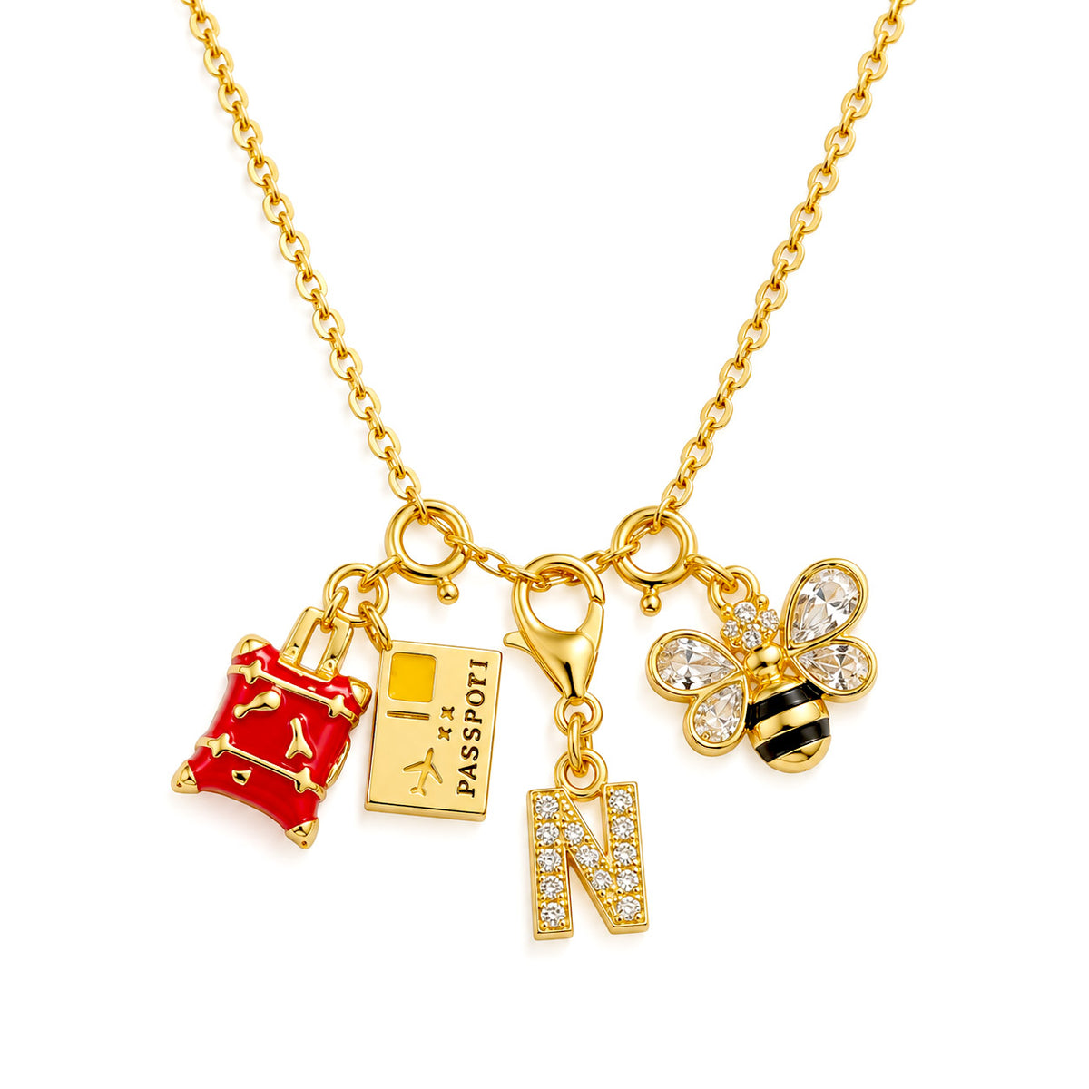 Gold-plated charm necklace featuring a red suitcase, passport, sparkling “N” initial, and bee charms on a delicate chain, displayed on a clean white background.