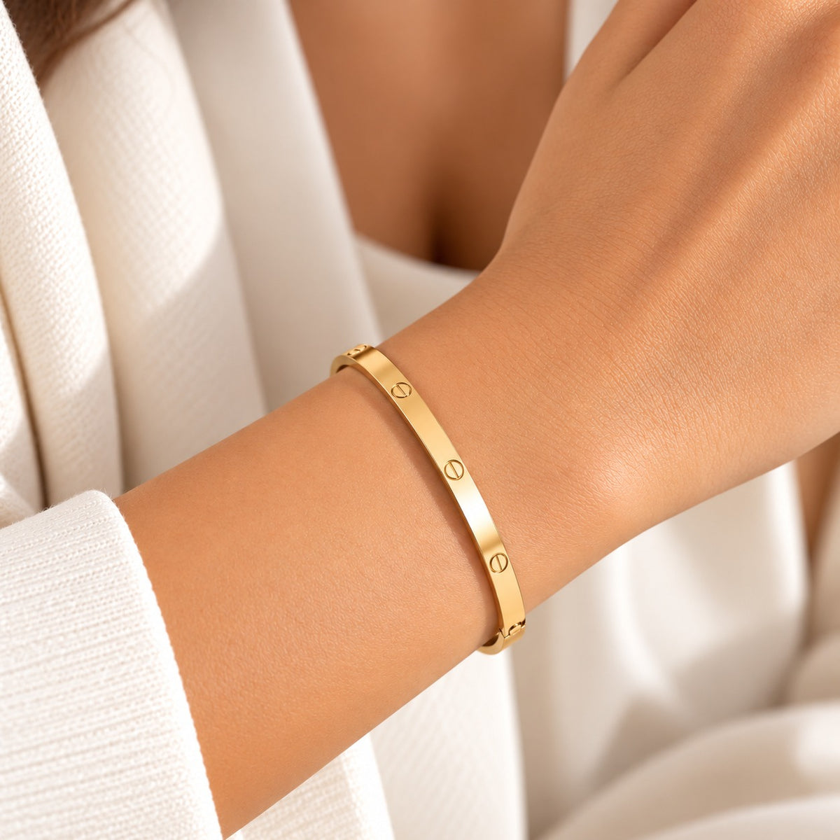 Gold anti-tarnish slim screw-design bangle worn on a model’s wrist with a cream outfit.