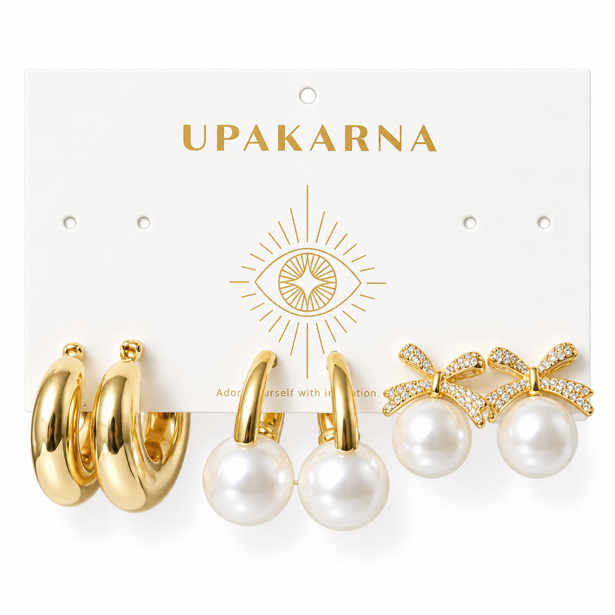 Three pairs of gold-plated statement earrings displayed on an Upakarna jewellery card, featuring chunky tube hoops, oversized pearl hoop earrings, and crystal-studded bow pearl stud earrings, arranged on a clean white background with a premium polished finish.