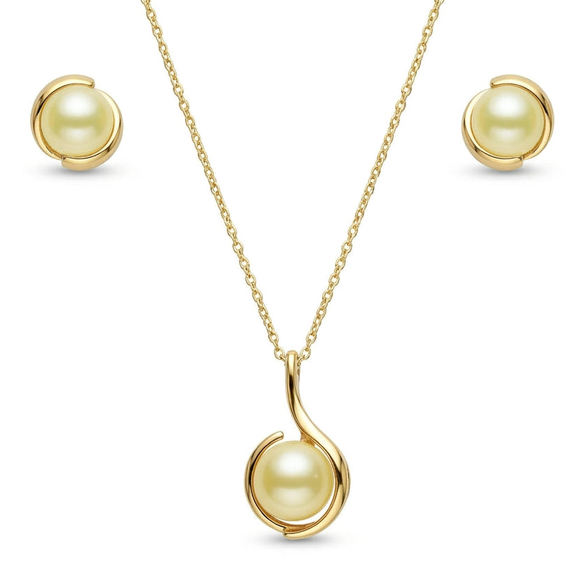 A yellow gold pearl jewelry set isolated on a plain white background, featuring a fine-chain necklace with a pendant that houses a golden pearl cradled within a fluid, swooping curved gold setting. The set is paired with matching stud earrings that feature identical golden pearls wrapped in sleek, complementary gold metal swirls.