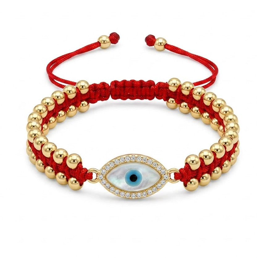 Red braided evil eye bracelet featuring polished gold beads and a central oval blue evil eye charm. The charm is surrounded by sparkling clear crystals, with adjustable red cord ends and gold bead accents. Displayed on a clean white background.
