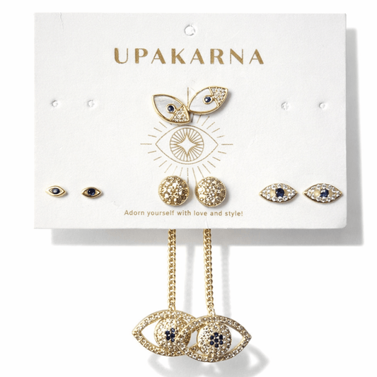 UPAKARNA evil eye earring collection featuring gold-tone stud earrings, sparkling eye-shaped designs, textured round studs, and elegant dangling evil eye earrings with navy-blue accents, displayed on ivory branded packaging against a clean white background.