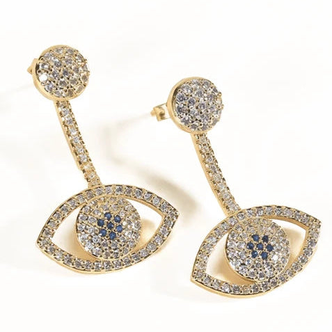 Gold-tone evil eye drop earrings featuring crystal-studded eye-shaped pendants with blue center motifs, connected to long crystal-encrusted bars and round stud tops.