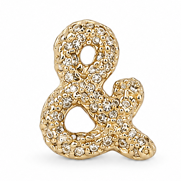 Gold ampersand jewellery charm embellished with multiple clear crystal stones on a white background.