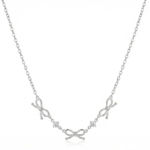 Silver-tone delicate necklace featuring three small bow-shaped charms along the lower center, with tiny crystal-like accents between the bows, arranged on a white background.