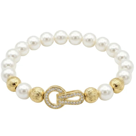 Gold-tone pearl bracelet featuring white pearl-like beads, textured gold beads, and a central crystal-encrusted toggle clasp with a rounded interlocking design.