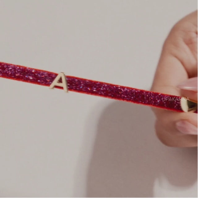 Video showcasing personalized glittery name bracelets, with gold-tone letter charms being added to colorful bands, followed by a lifestyle shot of the bracelets worn on the wrist.
