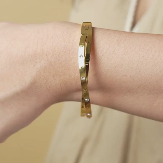 Roman-inspired twisted bangle with a sleek anti-tarnish finish, available in gold and rose gold, perfect for everyday wear, minimalist styling, and effortless layering
