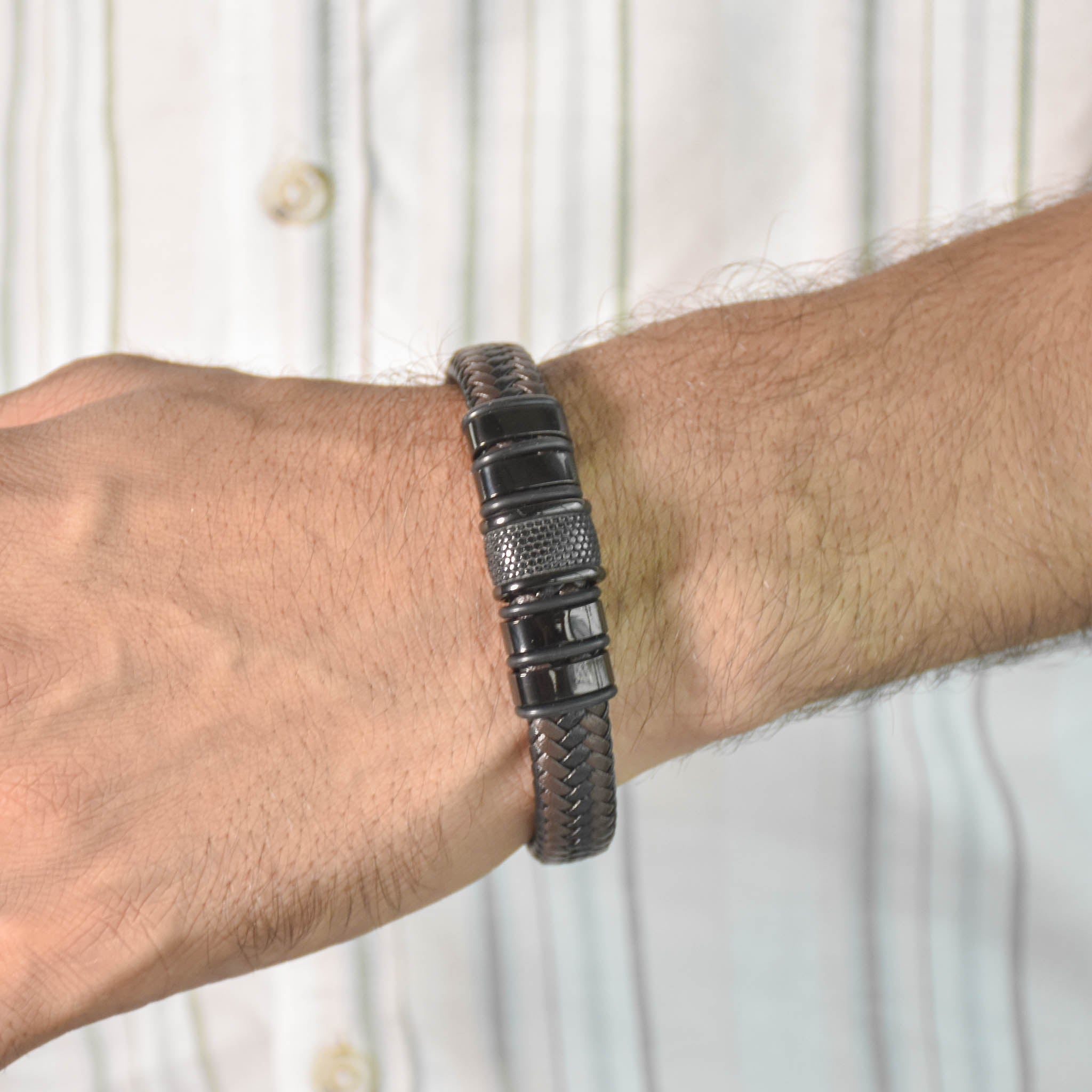 Braided leather bracelet with textured barrel accents and an anti-tarnish finish, perfect for everyday wear and modern masculine styling.
