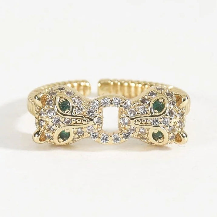 Gold-toned Tiger Loop Ring featuring an intricate symmetrical tiger-inspired design with green stone accents and sparkling pavé detailing, photographed on a clean white background.
