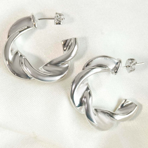 Silver-tone sculptural hoop earrings featuring overlapping, curved ribbon-like bands with a polished finish.